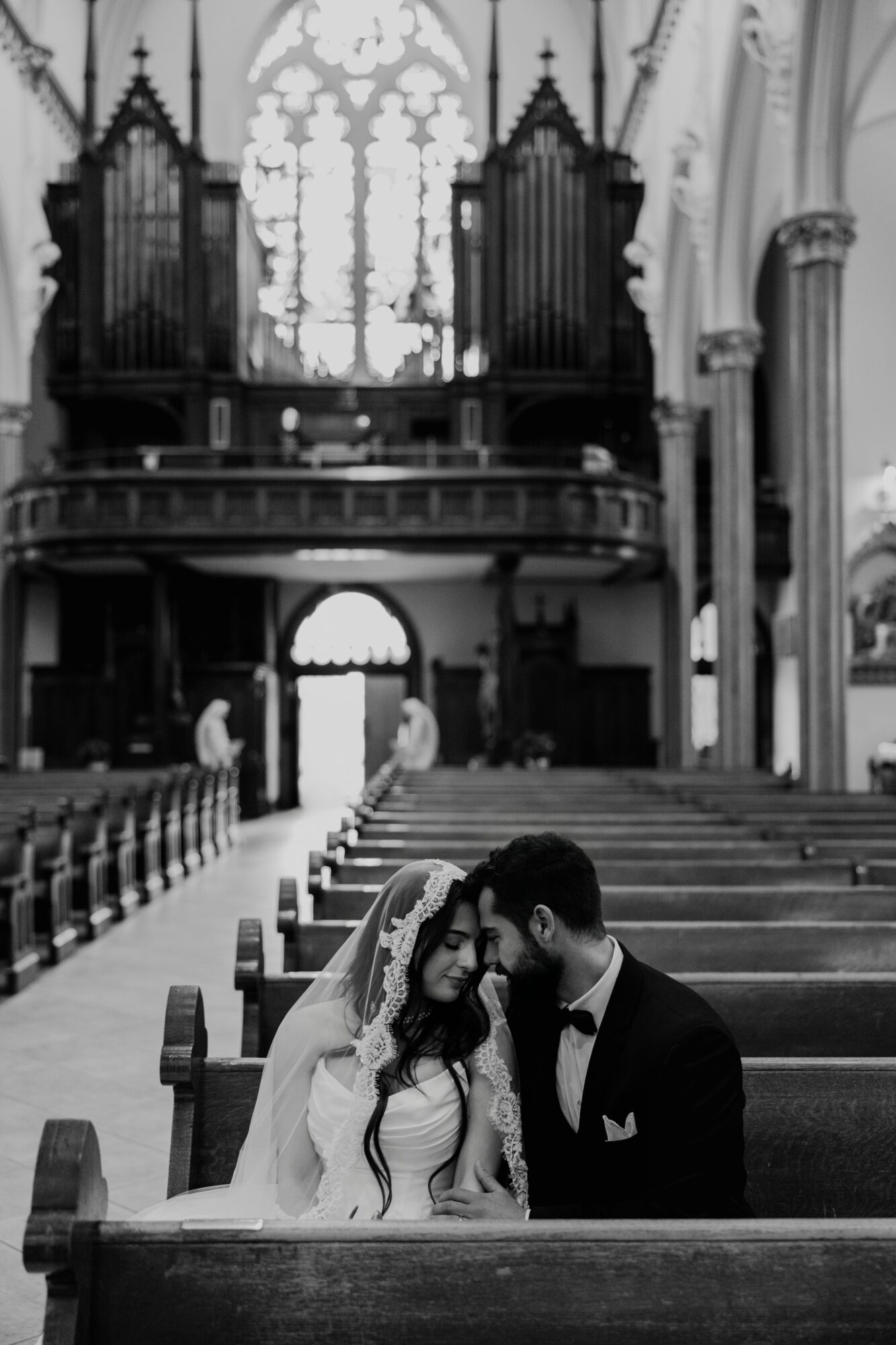 Couple sitting in church pew, facing each other, with an altar and organ in the background.