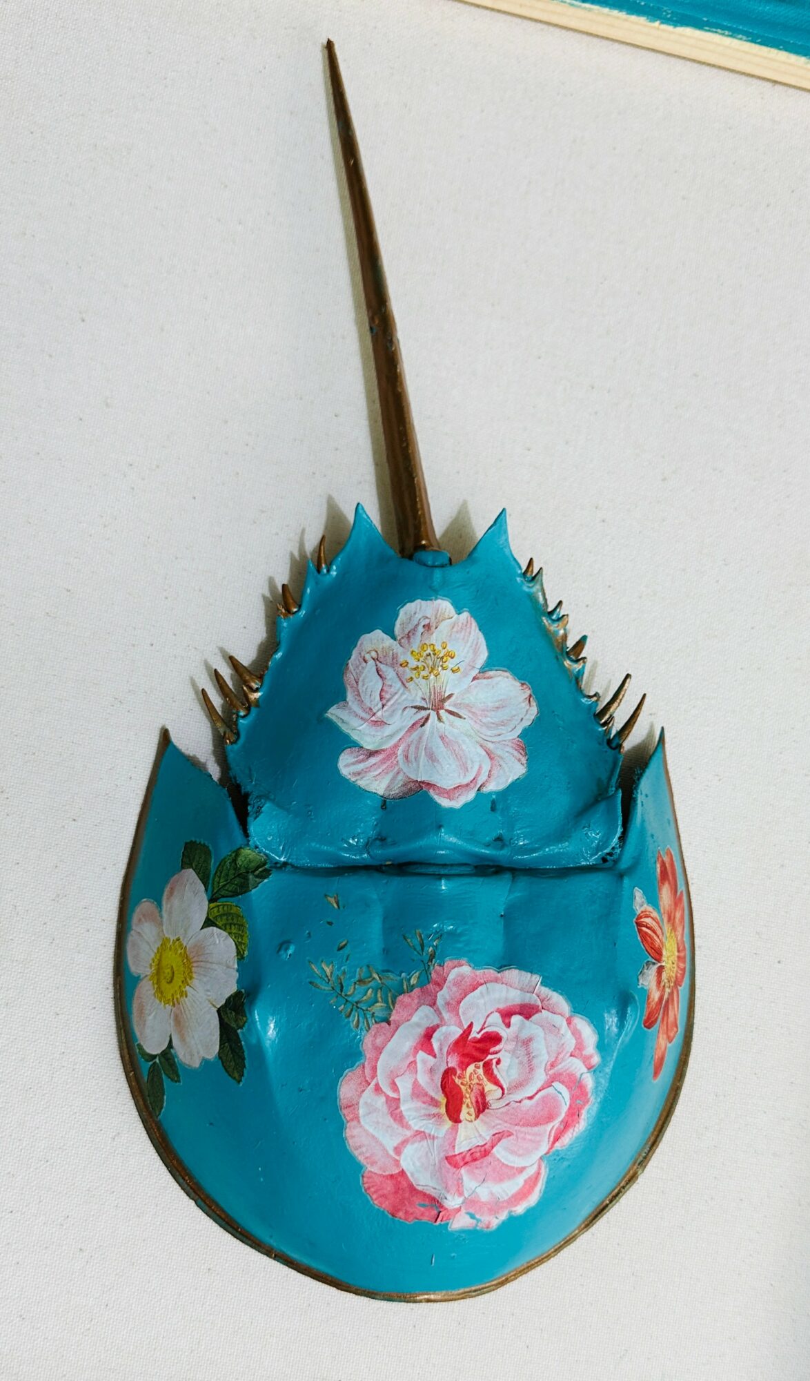 Decorative blue object with floral patterns and a pointed stick, viewed from the side.