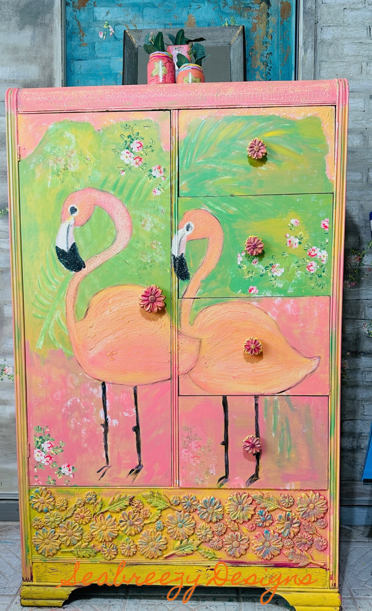 Colorful painted cabinet with two flamingos, flowers, and decorative elements, featuring pink, green, and yellow colors.