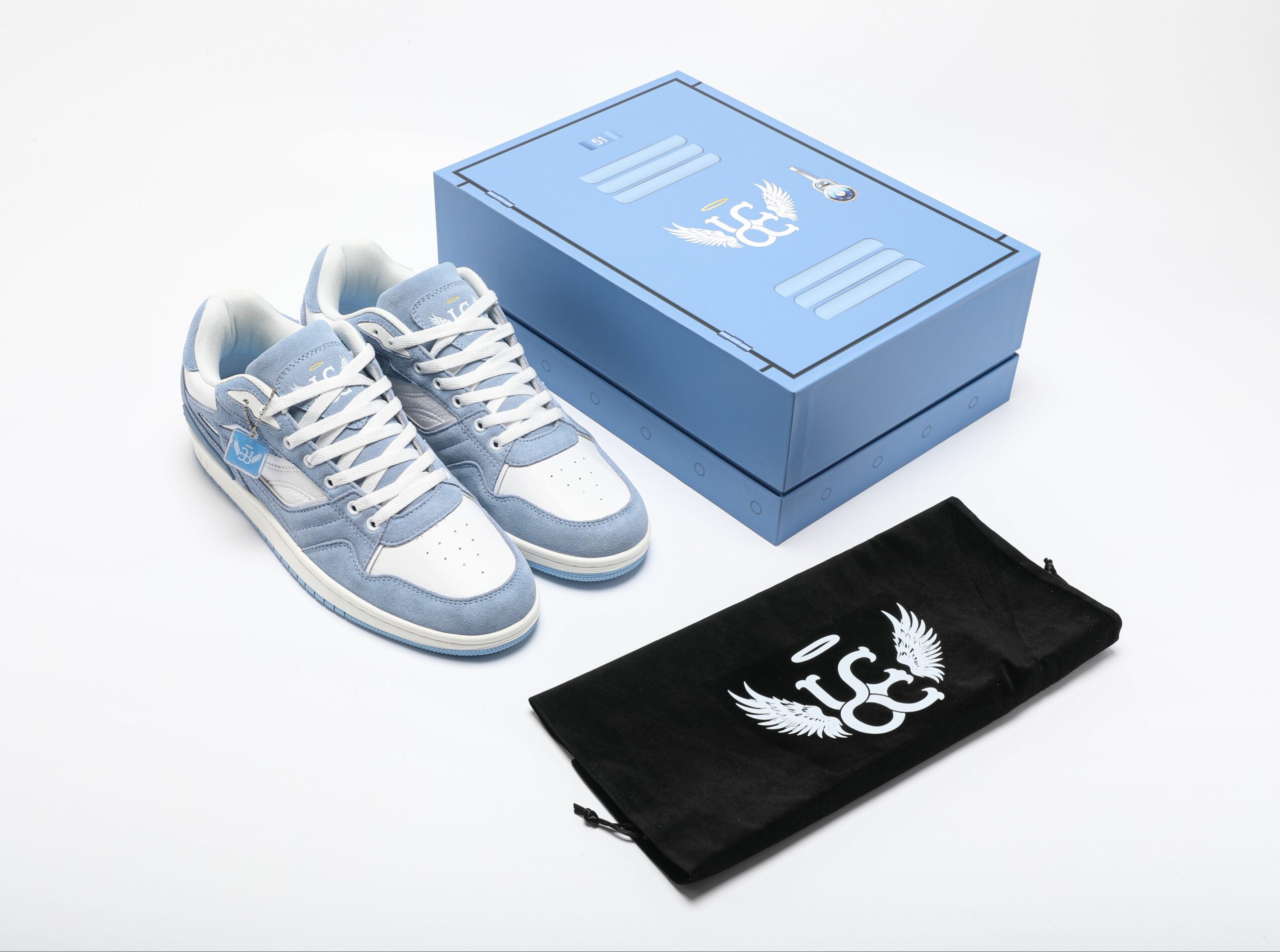 Pair of sneakers, blue shoe box, and black cloth with white logo on white background.