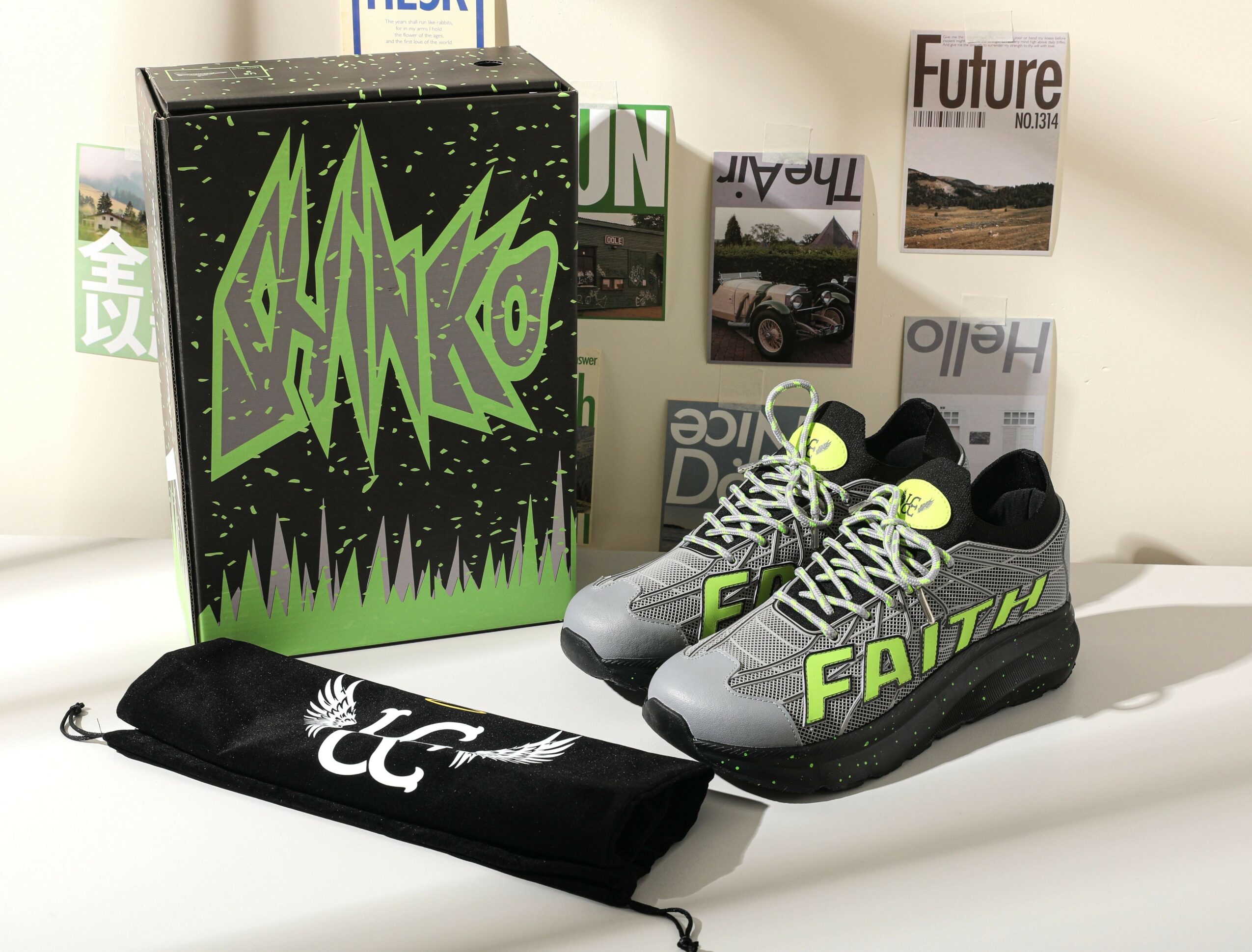 Pair of gray and black athletic shoes with neon green accents, a black drawstring bag, and a green box with graffiti-style text, on a white surface.