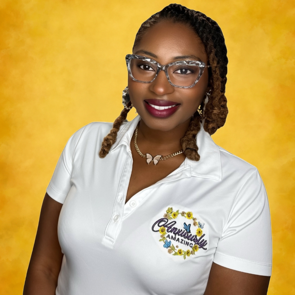 Woman with glasses and braided hair wearing a white polo shirt with a logo, smiling, yellow background.