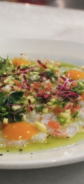 Plate with eggs, vegetables, and herbs, garnished with microgreens and drizzled with oil.