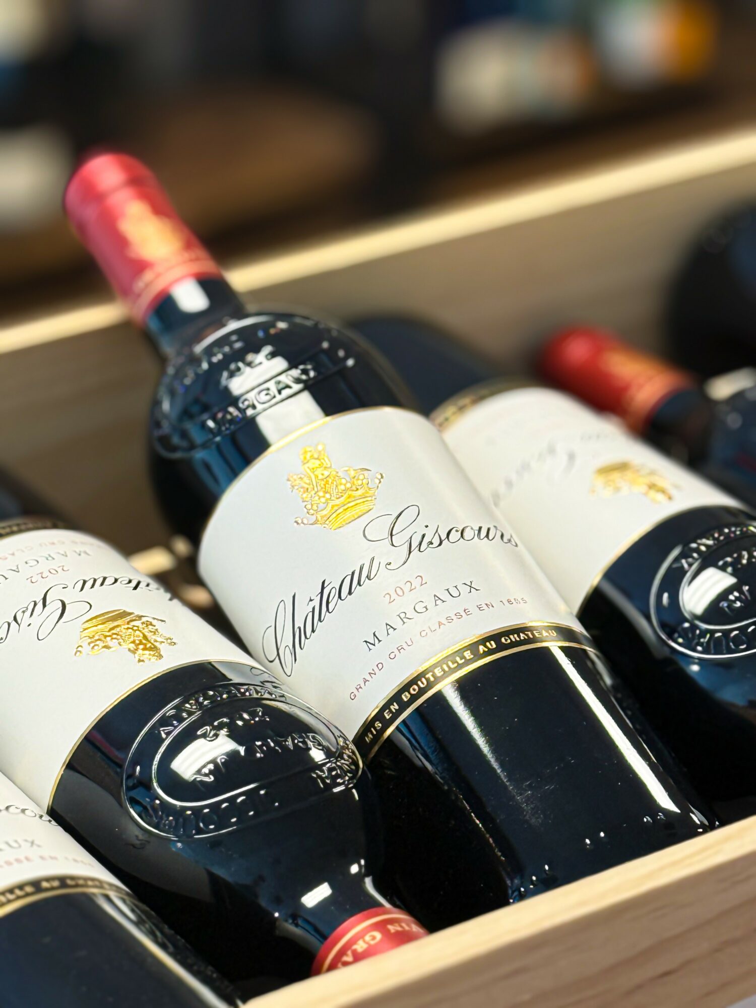 Several bottles of Château Giscours wine in a wooden box, with one bottle upright and others lying down.