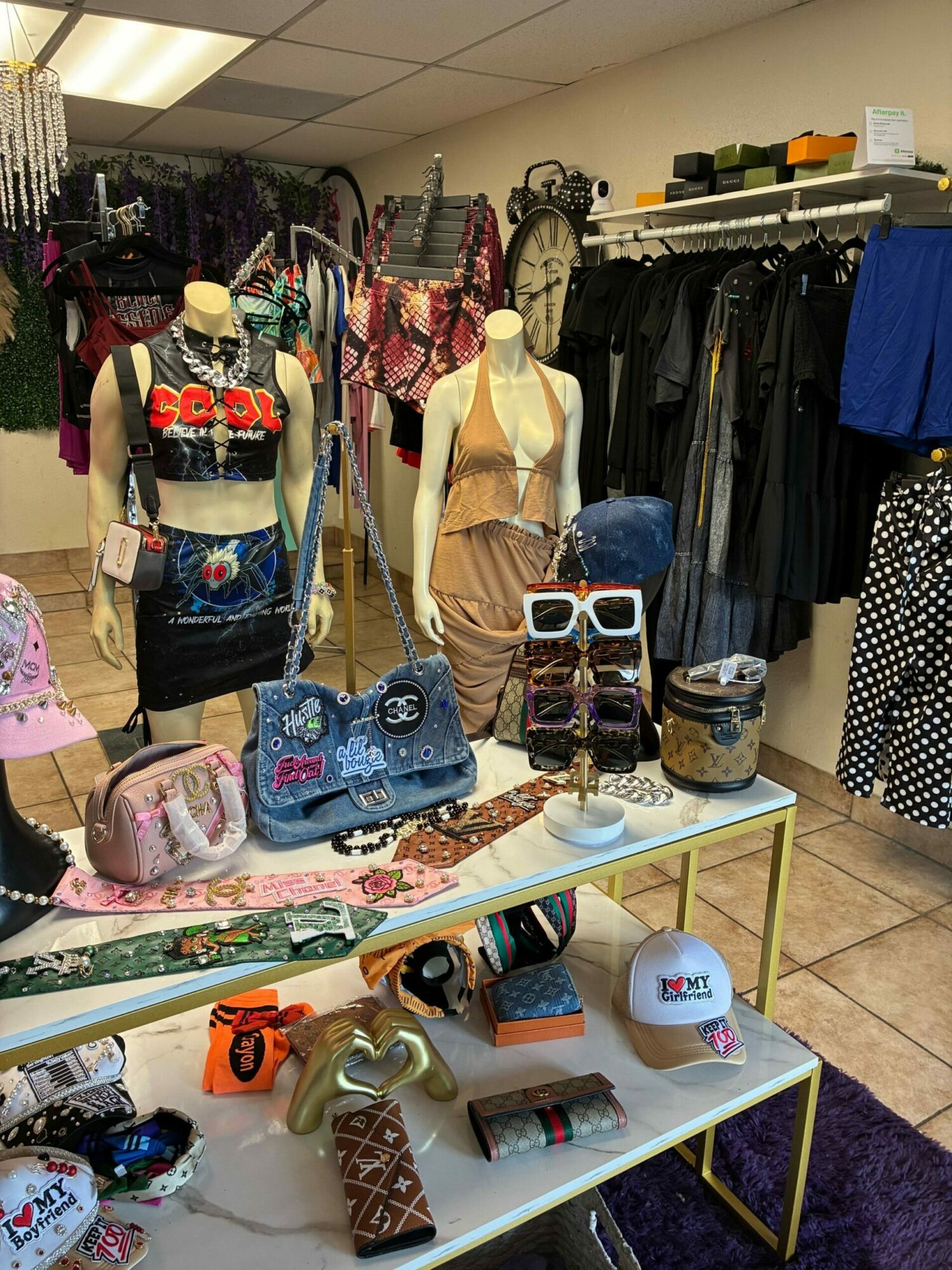 Display of handbags, accessories, and small items on tables and shelves in a store.