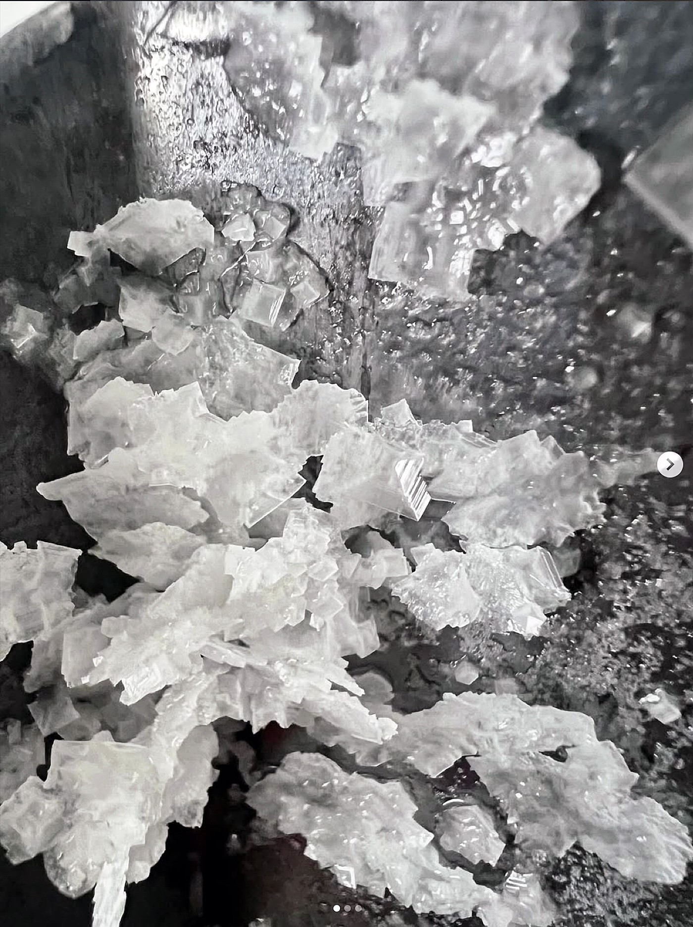 Crushed ice scattered on a dark surface with some ice fragments in the background.