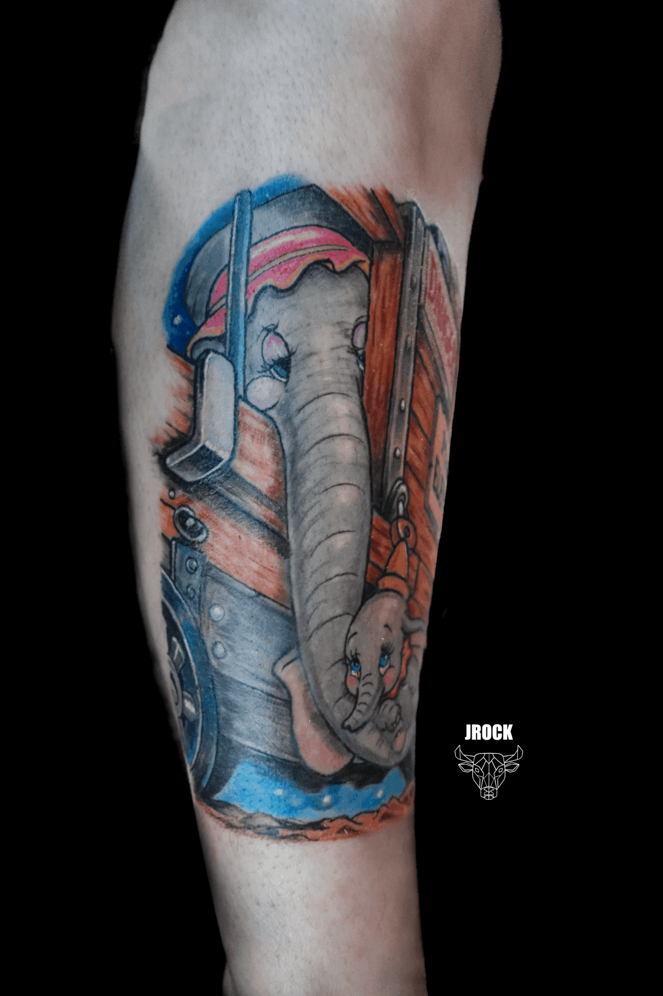 Colorful tattoo of an elephant with headphones, surrounded by water and wooden elements, on a person's arm.