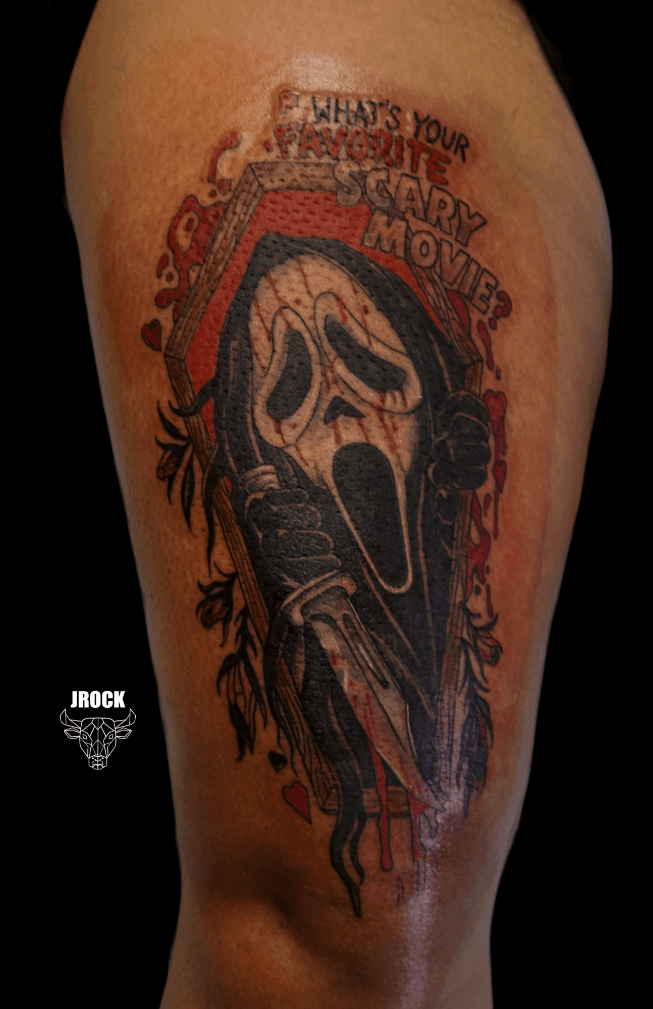 Tattoo of a ghostface mask from Scream with a red background and text, on a person's arm.