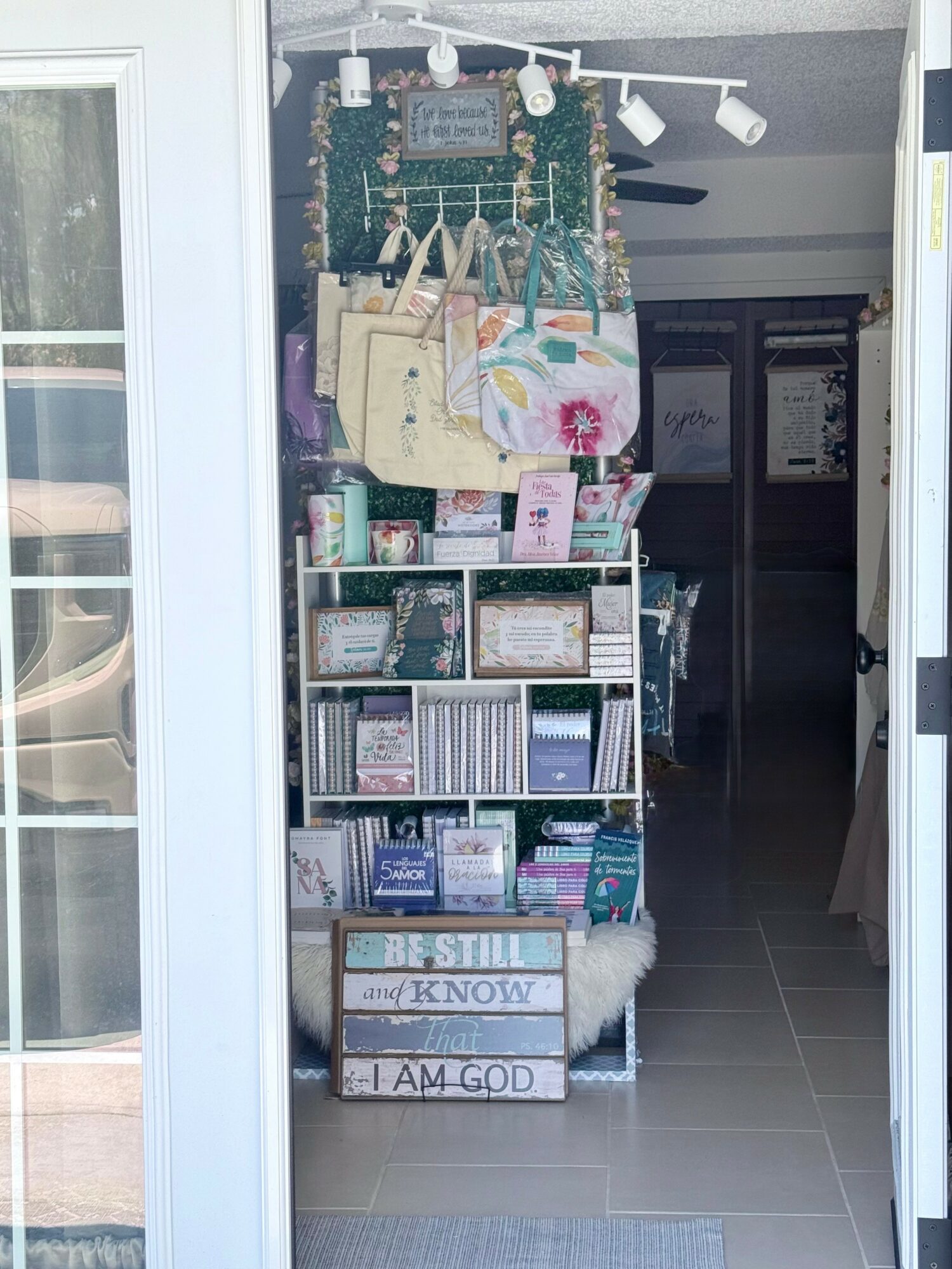 Shelf with decorative items, books, and signs inside a store entrance, with a tiled floor and dark interior background.
