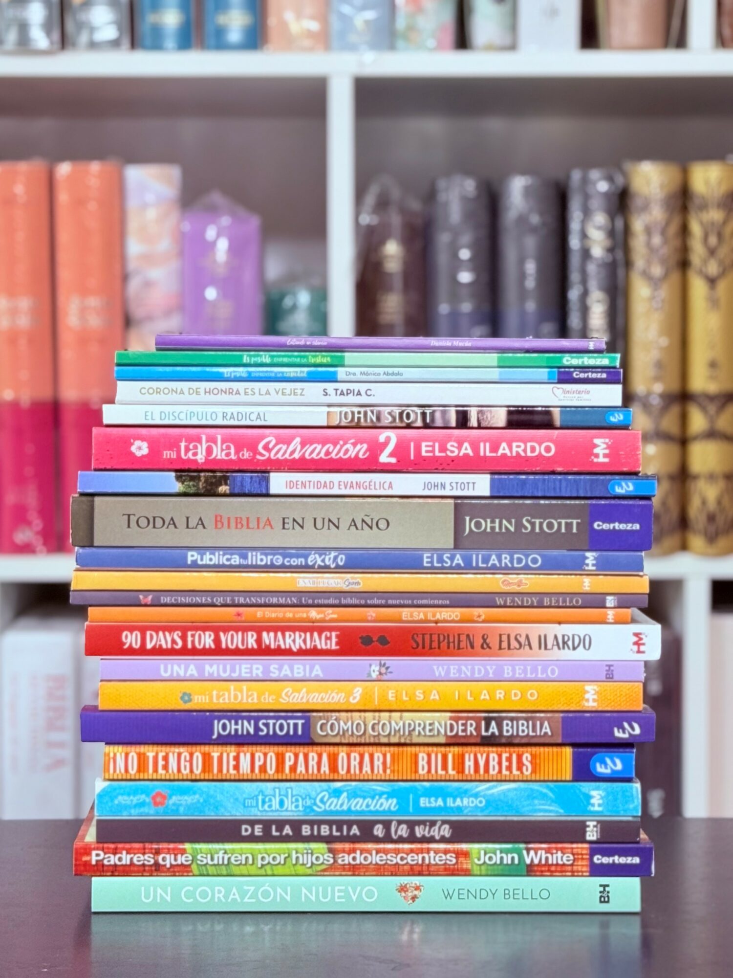 Stack of colorful books on a shelf with a blurred background of more books.