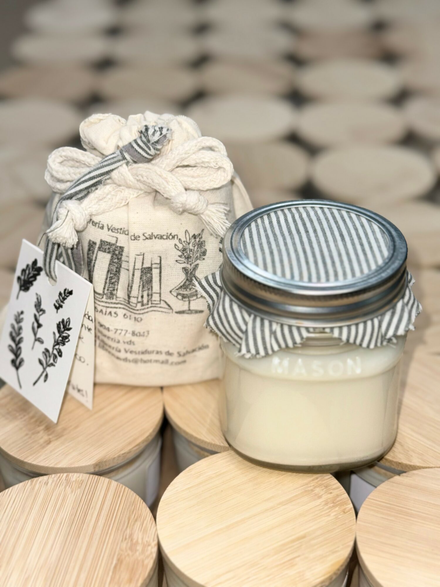 A jar with a striped cloth cover and a drawstring bag with a botanical illustration, placed on a wooden surface.