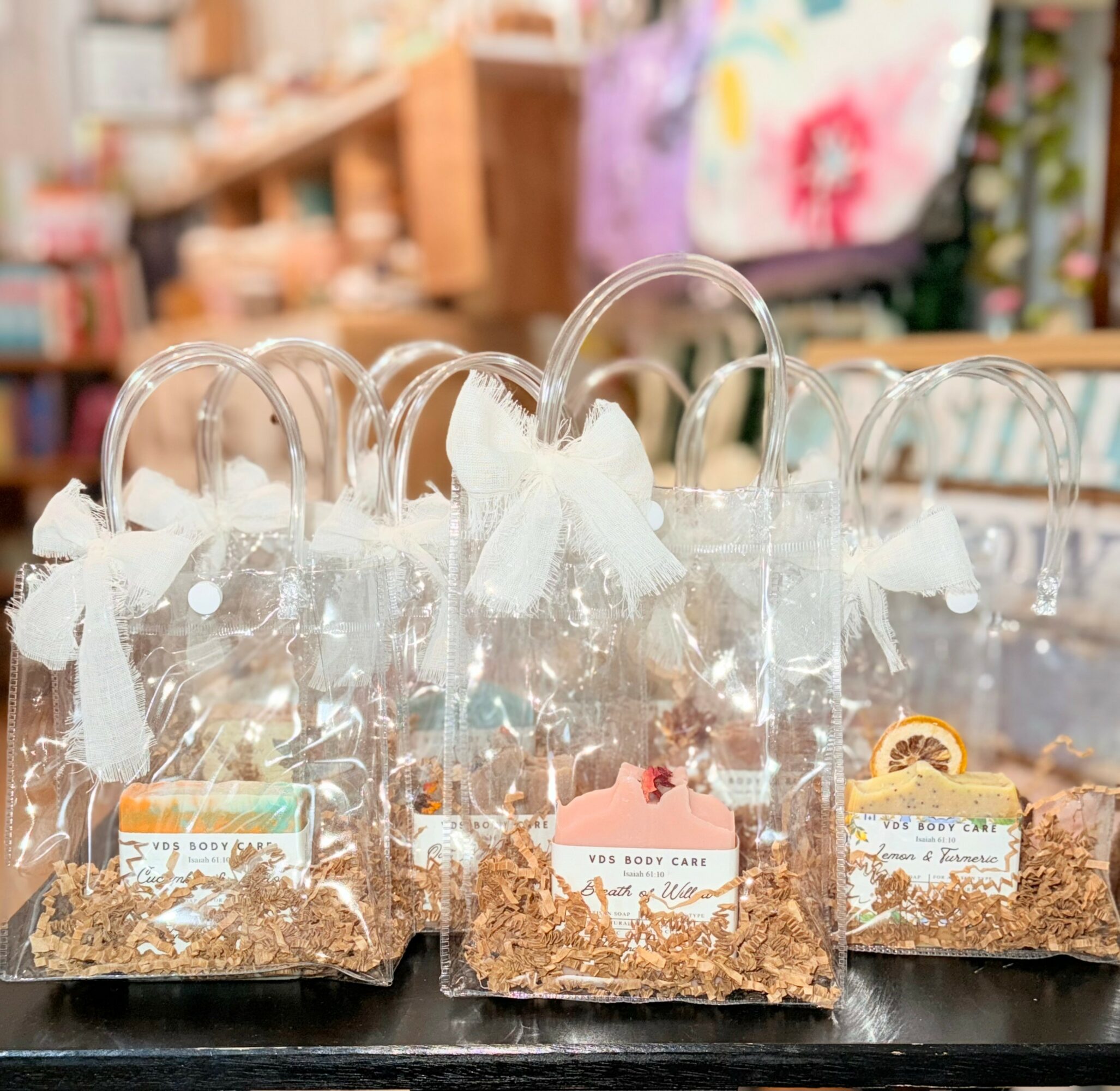 Clear plastic bags filled with white tissue paper and small items, displayed on a black surface with a blurred store background.