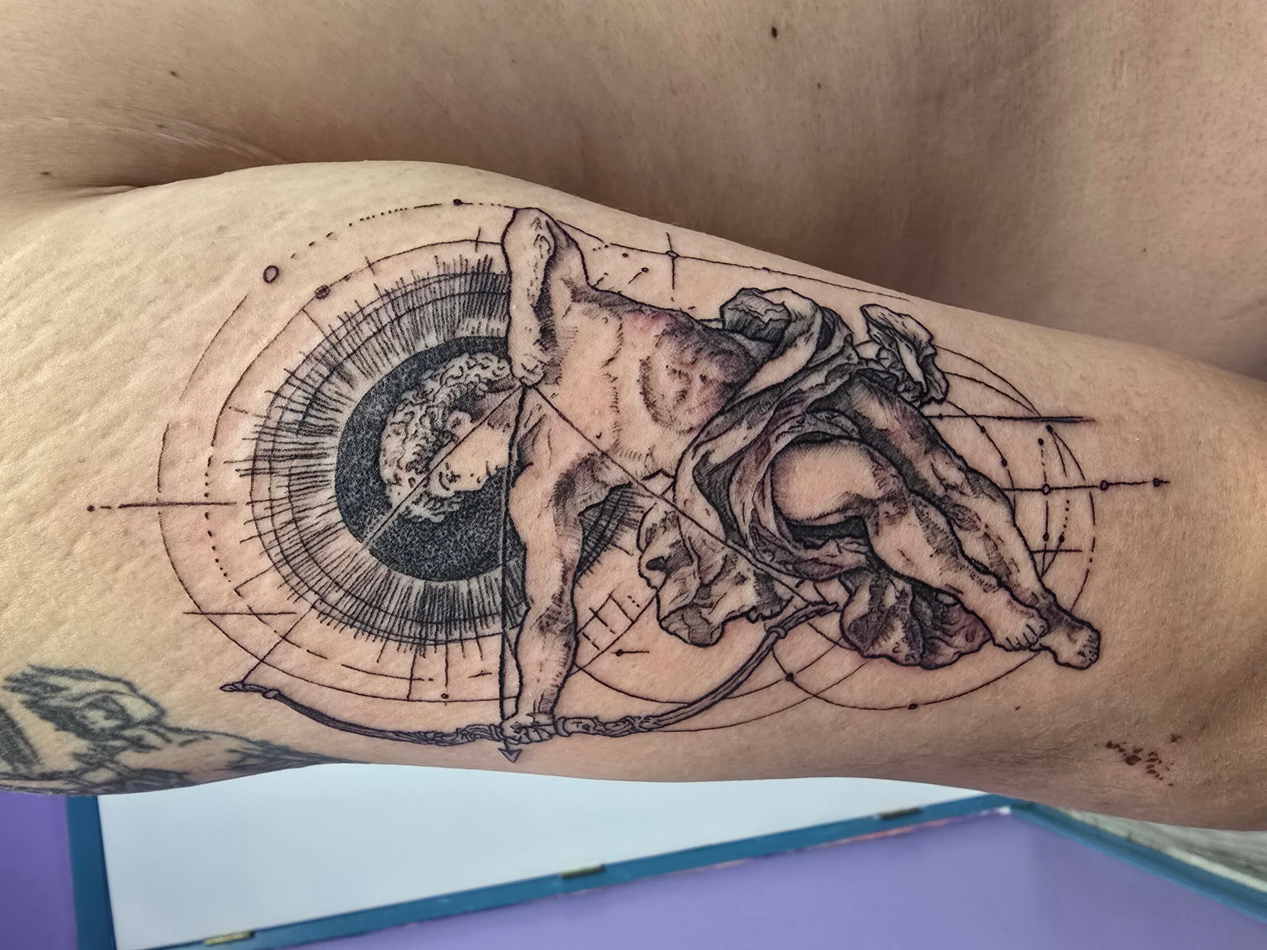 Tattoo of a detailed animal skull with geometric and circular patterns behind it on skin.