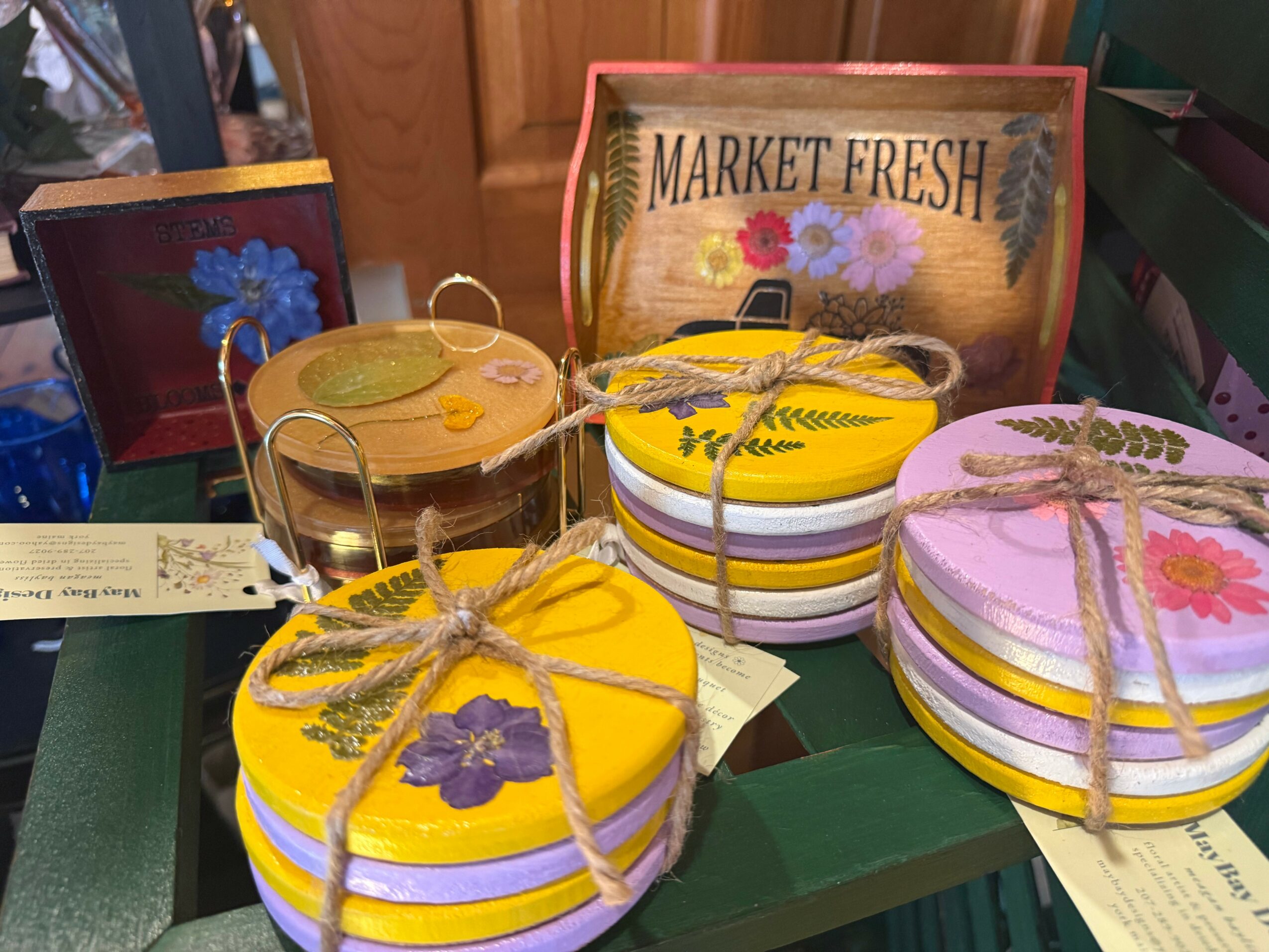 Stacked colorful plates with yellow, purple, and white stripes tied with twine, a glass of iced tea, and decorative signs on a table.