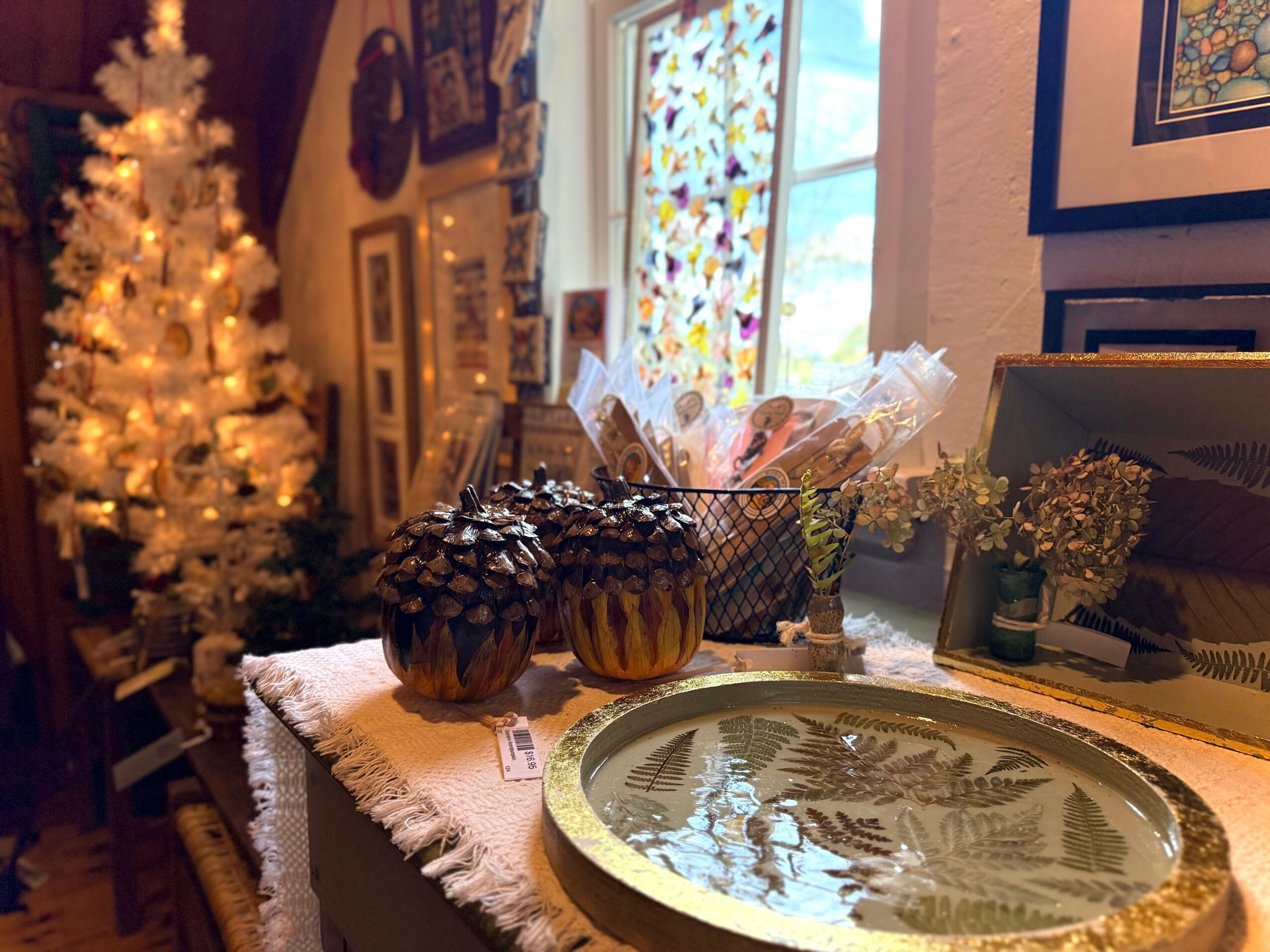Decorated table with baked goods, a tray, and flowers near a window with stained glass, in a cozy room.