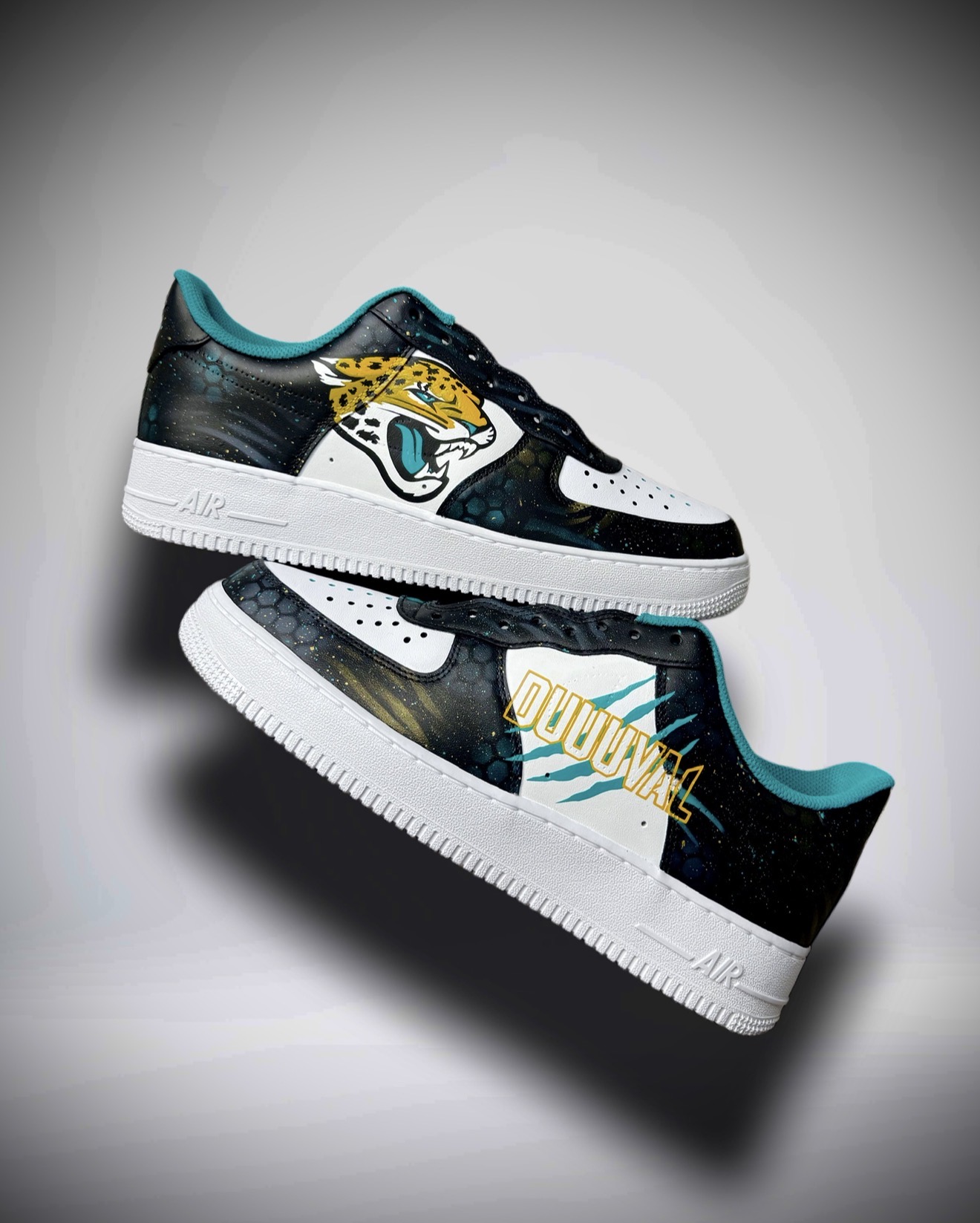 Pair of sneakers with black, white, teal, and yellow colors, placed on a gray background. One shoe is upright, the other tilted.