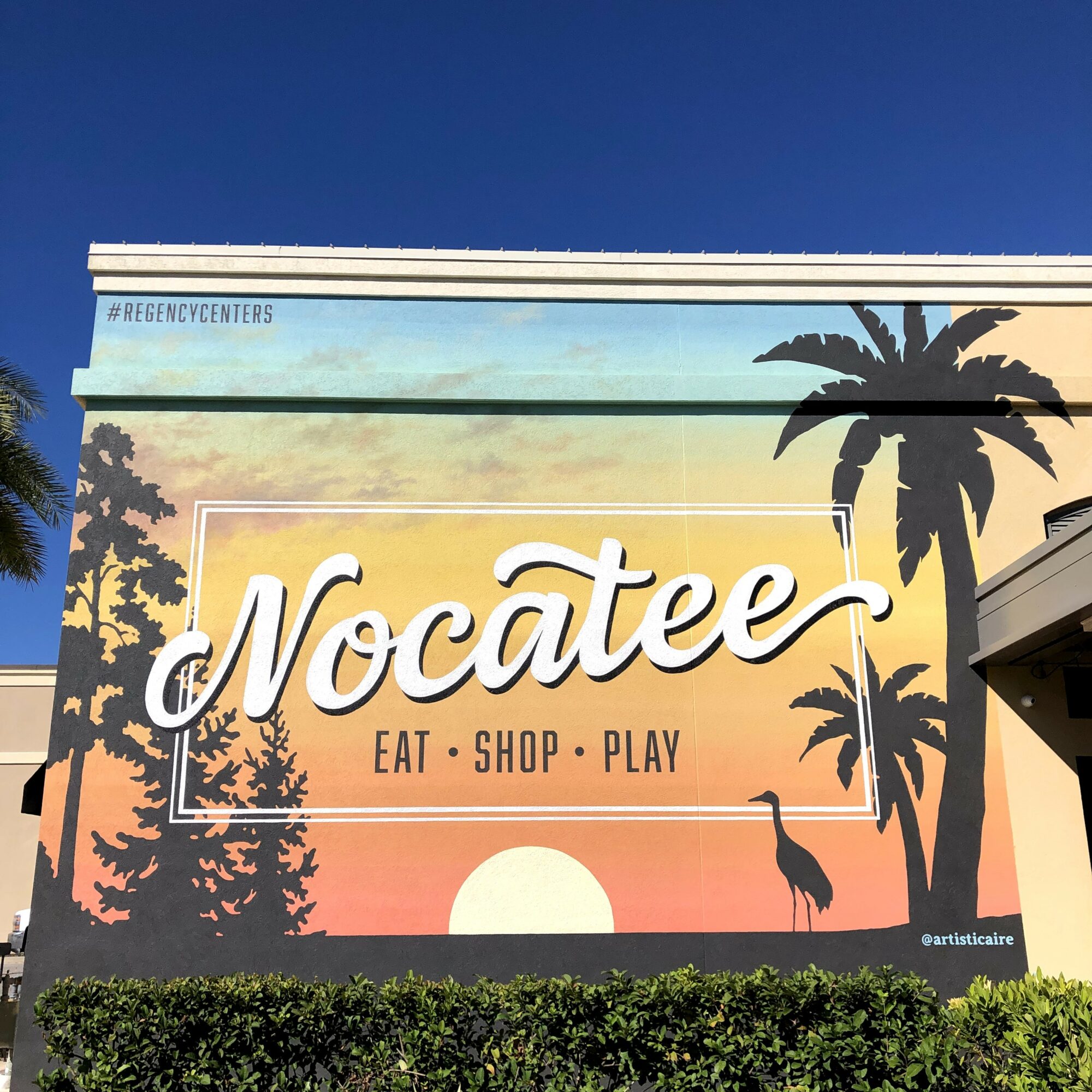 Large colorful mural with the word 'Nocatee' and the phrase 'Eat, Shop, Play' with palm trees and a sunset background.