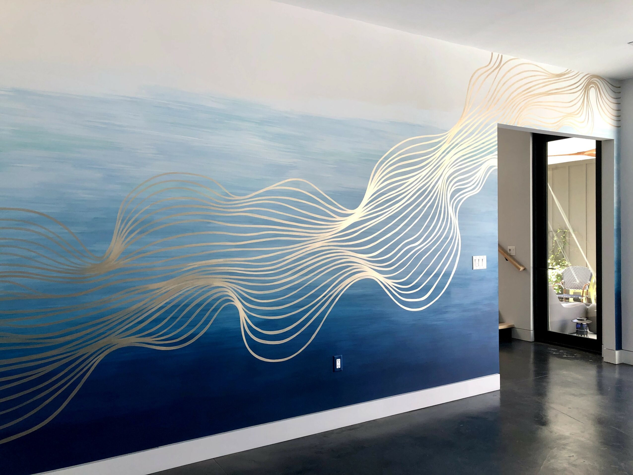 Wall mural with flowing white lines on a blue background, next to an open doorway leading outside.